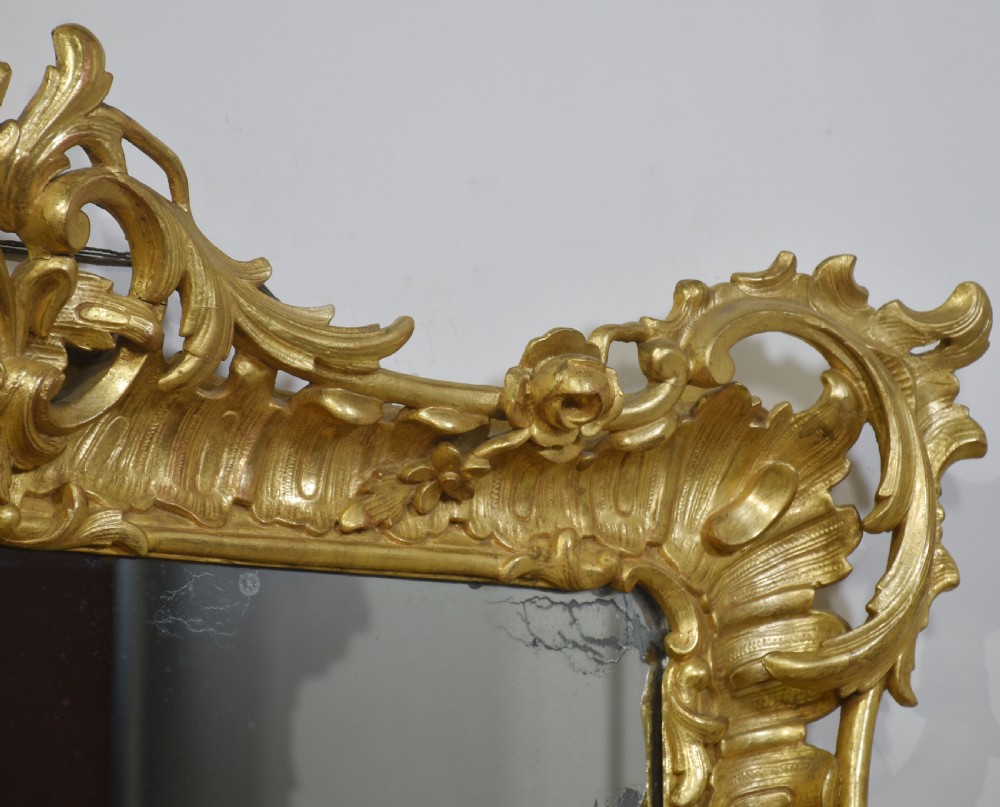 A 19th-century rectangular wall mirror featuring an ornate giltwood frame carved with Rococo C-scrolls and floral motifs. View IX