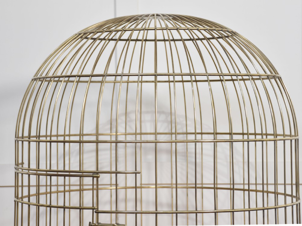 A large brass domed bird cage with a polished copper basin resting upon a grey wrought iron scrollwork stand. View III