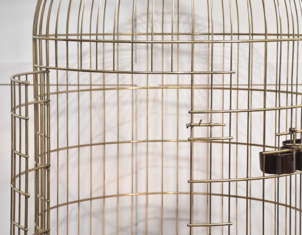 A large brass domed bird cage with a polished copper basin resting upon a grey wrought iron scrollwork stand. View VII