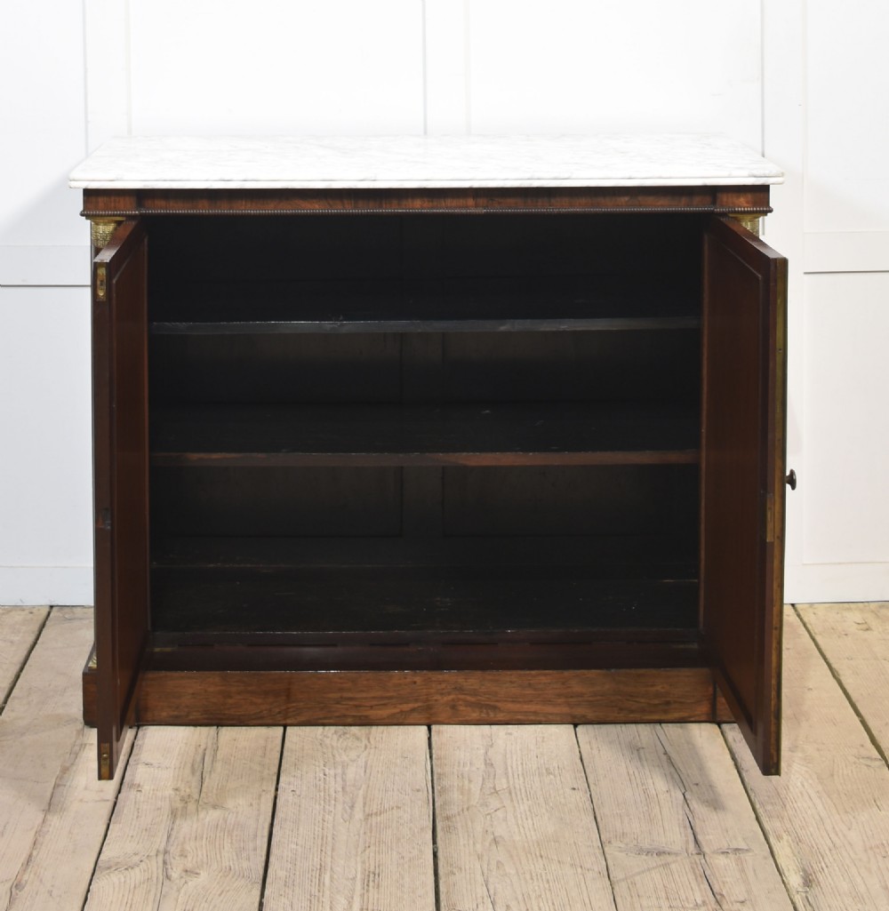 A nineteenth-century dark rosewood two-door cabinet featuring a white marble top, brass grille doors with pleated fabric lining, and columnar side supports. View II