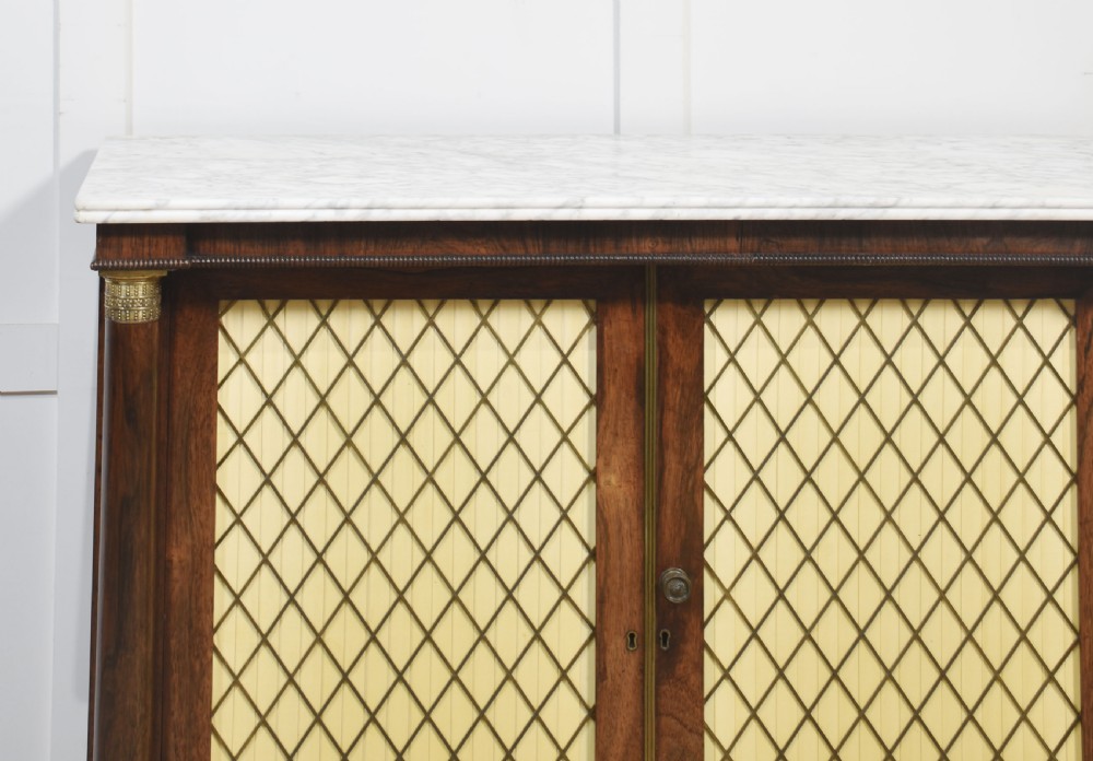 A nineteenth-century dark rosewood two-door cabinet featuring a white marble top, brass grille doors with pleated fabric lining, and columnar side supports. View III