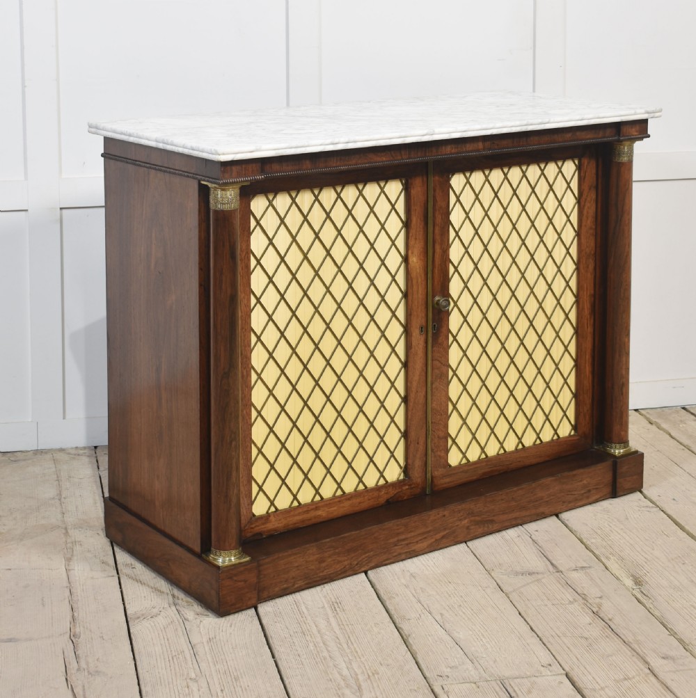 A nineteenth-century dark rosewood two-door cabinet featuring a white marble top, brass grille doors with pleated fabric lining, and columnar side supports. View VIII