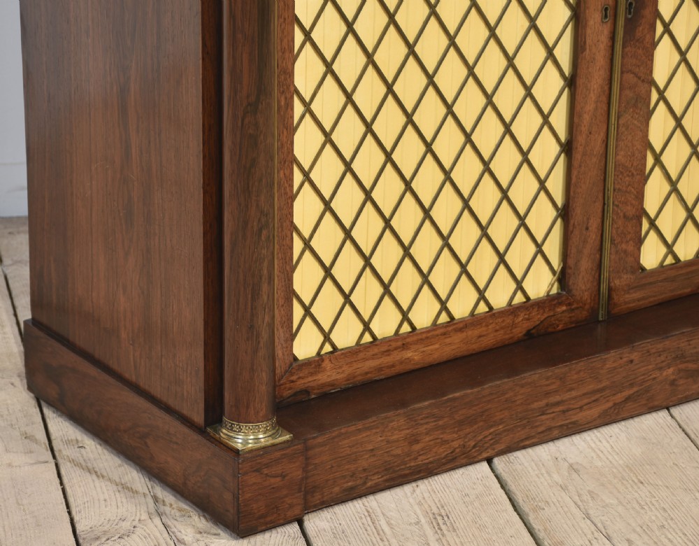 A nineteenth-century dark rosewood two-door cabinet featuring a white marble top, brass grille doors with pleated fabric lining, and columnar side supports. View IX
