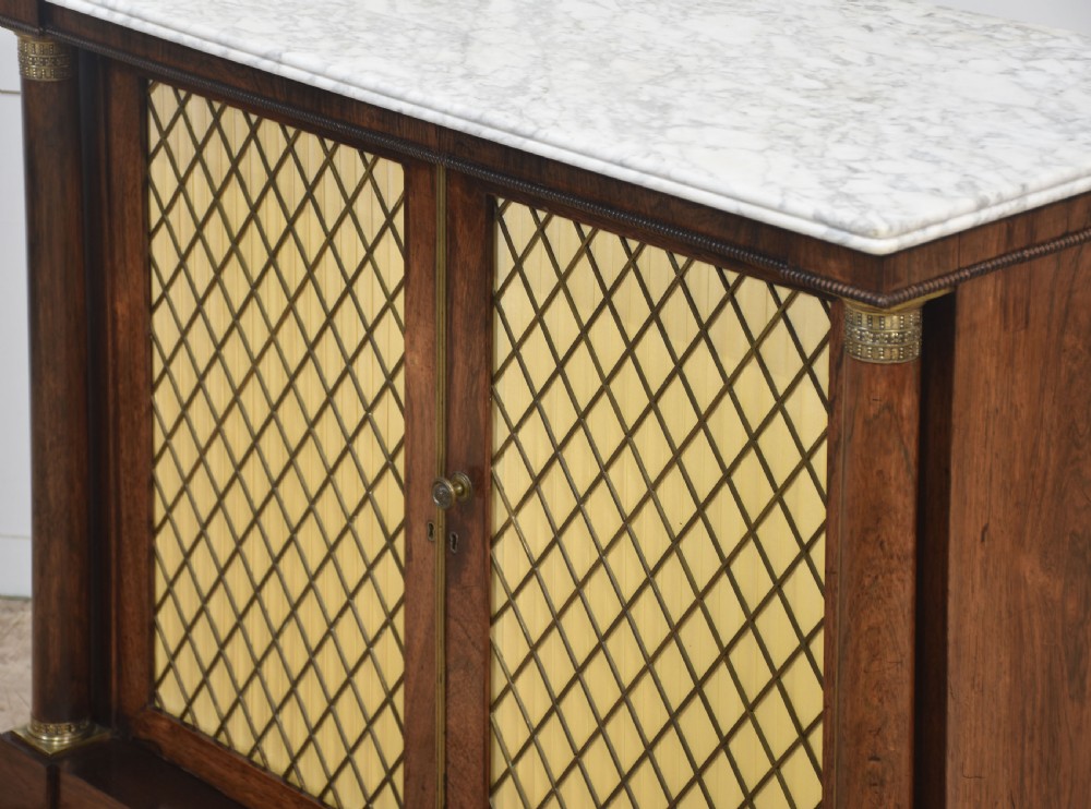 A nineteenth-century dark rosewood two-door cabinet featuring a white marble top, brass grille doors with pleated fabric lining, and columnar side supports. View XII