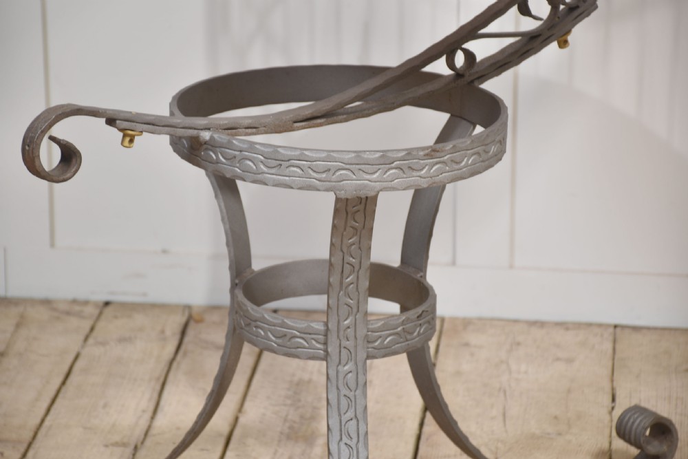 A domed brass bird cage with a copper base tray, suspended from a grey crescent-shaped wrought iron stand. View VIII