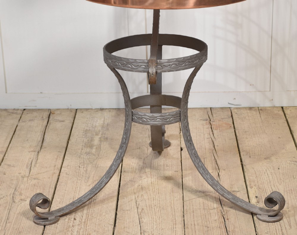 A domed brass bird cage with a copper base tray, suspended from a grey crescent-shaped wrought iron stand. View IX