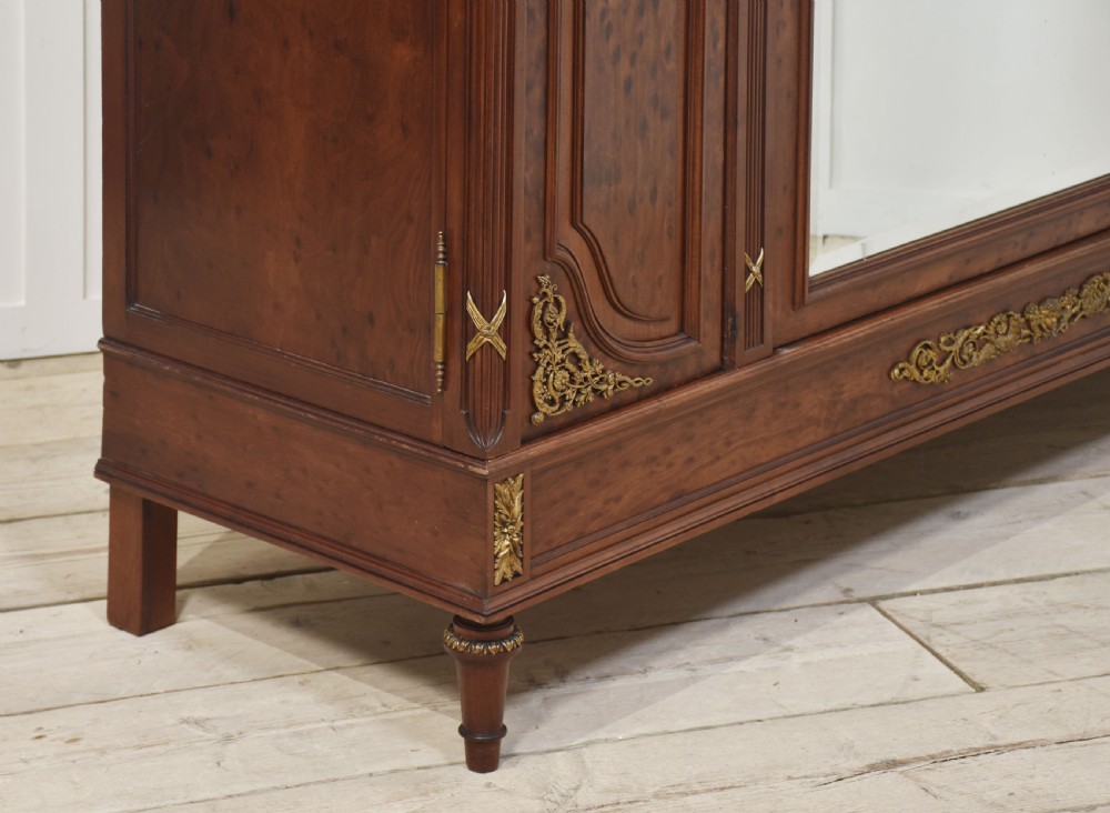 A 19th-century French Louis XVI mahogany wardrobe featuring a central arched mirrored door flanked by twin panelled side doors with gilt bronze mounts. View IX