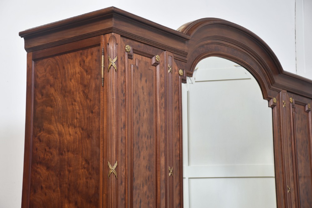 A 19th-century French Louis XVI mahogany wardrobe featuring a central arched mirrored door flanked by twin panelled side doors with gilt bronze mounts. View X
