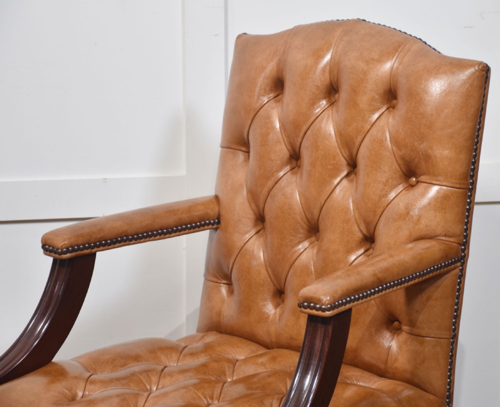 A pair of Georgian style tan leather Gainsborough library chairs featuring deep buttoned upholstery, brass studding, and dark mahogany frames. View II