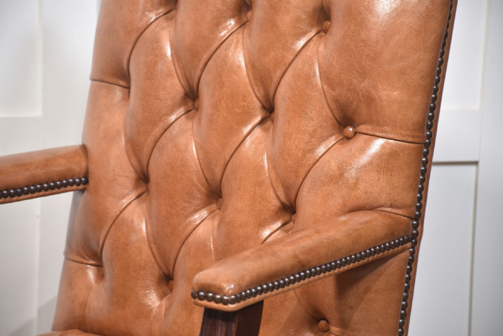 A pair of Georgian style tan leather Gainsborough library chairs featuring deep buttoned upholstery, brass studding, and dark mahogany frames. View VI