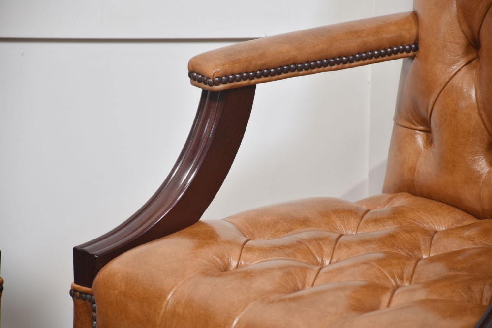 A pair of Georgian style tan leather Gainsborough library chairs featuring deep buttoned upholstery, brass studding, and dark mahogany frames. View VIII