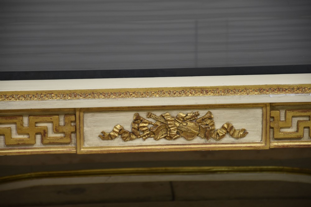 A low rectangular Venetian style coffee table featuring a black stone top, cream painted frieze with gold Greek key carving, and parcel gilt fluted legs. View X