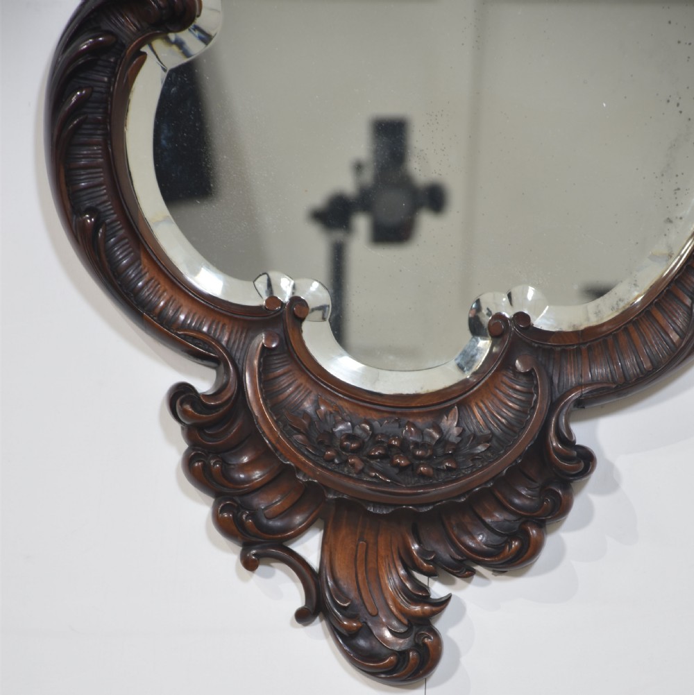 An asymmetrical Rococo Revival wall mirror with an intricately carved mahogany frame featuring C-scrolls and acanthus leaves around a shaped glass plate. View VII