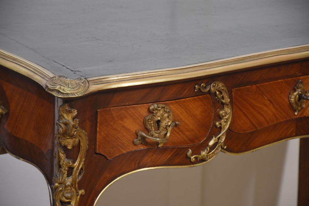 A nineteenth-century French bureau plat desk with cabriole legs, a leather writing surface, and ornate gilt bronze corner mounts. View III
