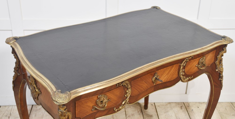 A nineteenth-century French bureau plat desk with cabriole legs, a leather writing surface, and ornate gilt bronze corner mounts. View VI
