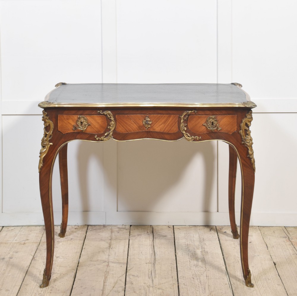 A nineteenth-century French bureau plat desk with cabriole legs, a leather writing surface, and ornate gilt bronze corner mounts. View VII