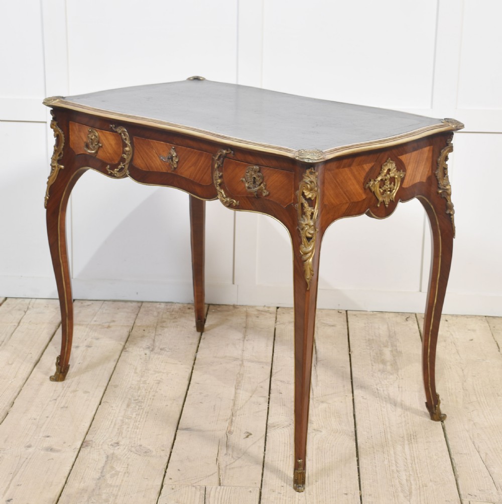 A nineteenth-century French bureau plat desk with cabriole legs, a leather writing surface, and ornate gilt bronze corner mounts. View X