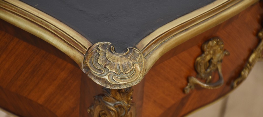 A nineteenth-century French bureau plat desk with cabriole legs, a leather writing surface, and ornate gilt bronze corner mounts. View XIII
