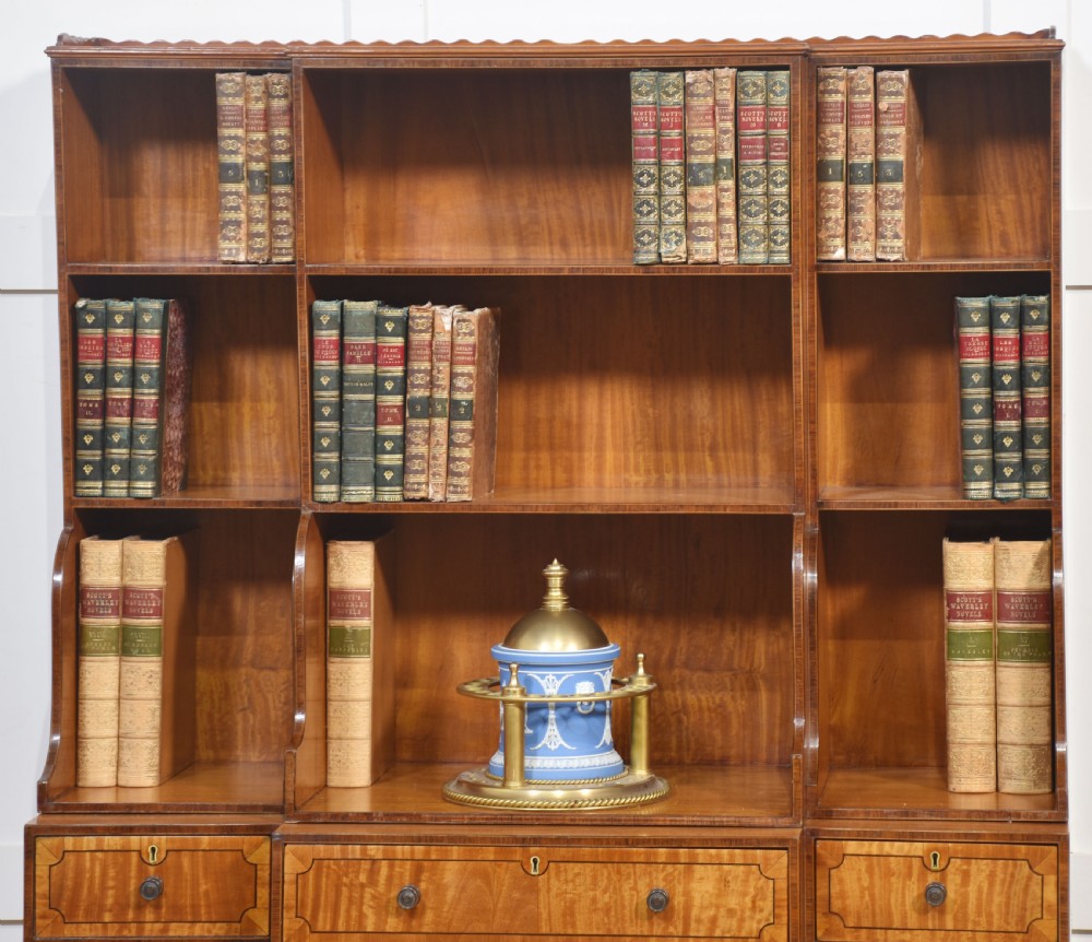 A matching pair of open satinwood breakfront bookcases featuring stepped waterfall shelving, inlaid drawers, and oval panel cupboard doors. View VII