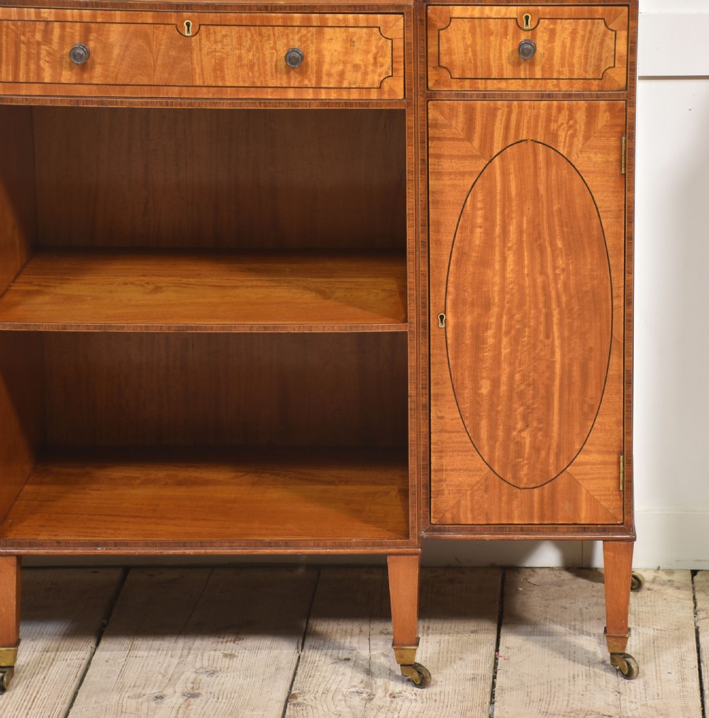 A matching pair of open satinwood breakfront bookcases featuring stepped waterfall shelving, inlaid drawers, and oval panel cupboard doors. View VIII