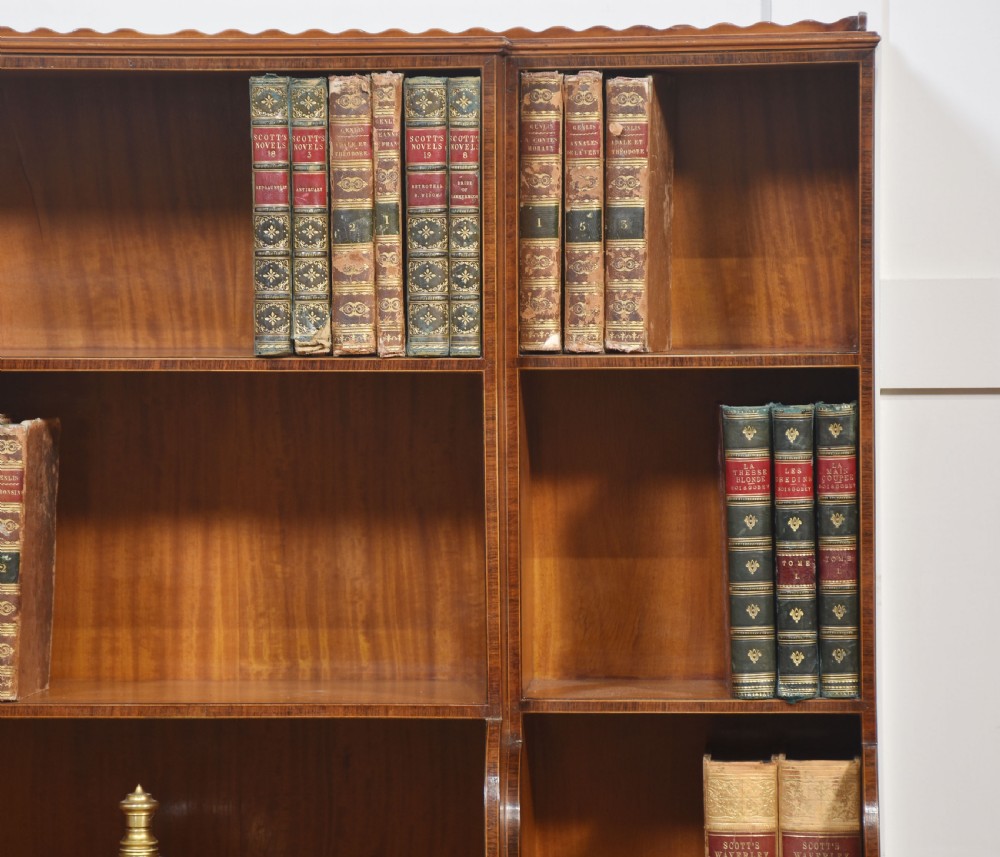 A matching pair of open satinwood breakfront bookcases featuring stepped waterfall shelving, inlaid drawers, and oval panel cupboard doors. View IX