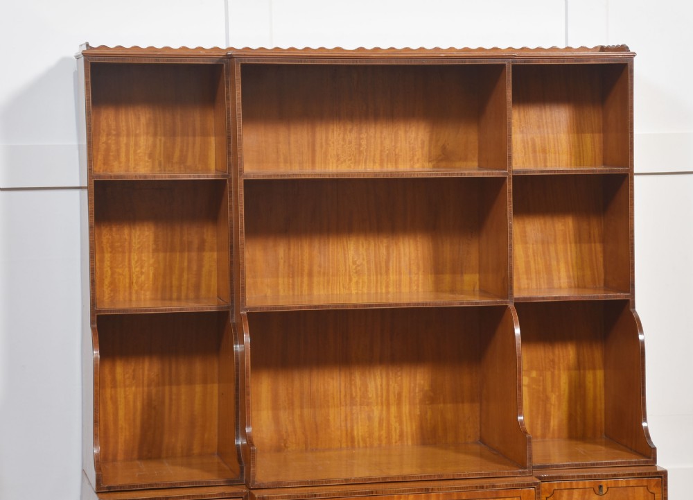 A matching pair of open satinwood breakfront bookcases featuring stepped waterfall shelving, inlaid drawers, and oval panel cupboard doors. View XIV