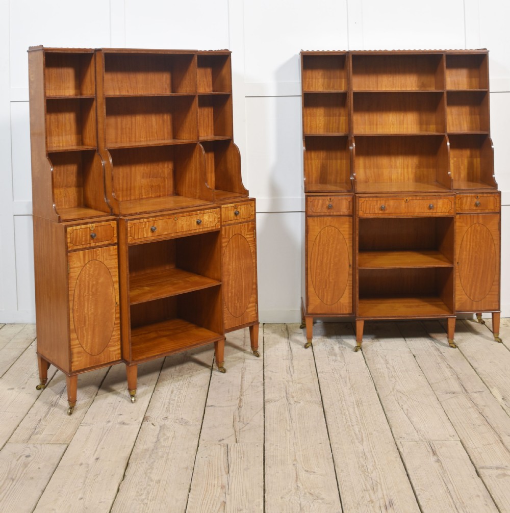 A matching pair of open satinwood breakfront bookcases featuring stepped waterfall shelving, inlaid drawers, and oval panel cupboard doors. View XV