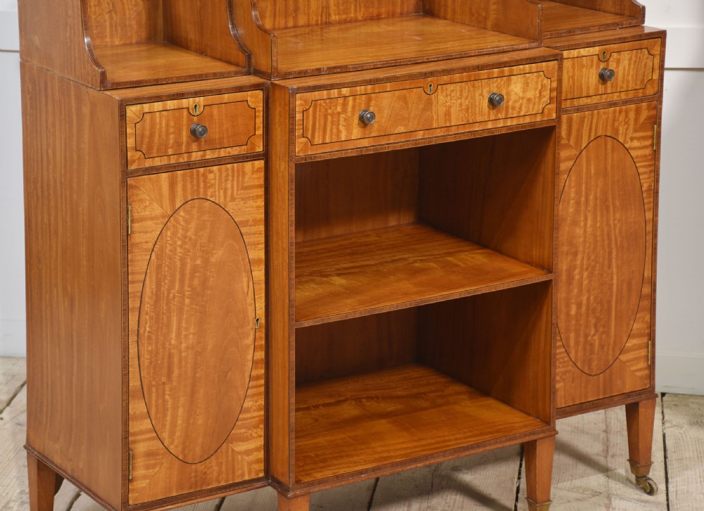 A matching pair of open satinwood breakfront bookcases featuring stepped waterfall shelving, inlaid drawers, and oval panel cupboard doors. View XVI