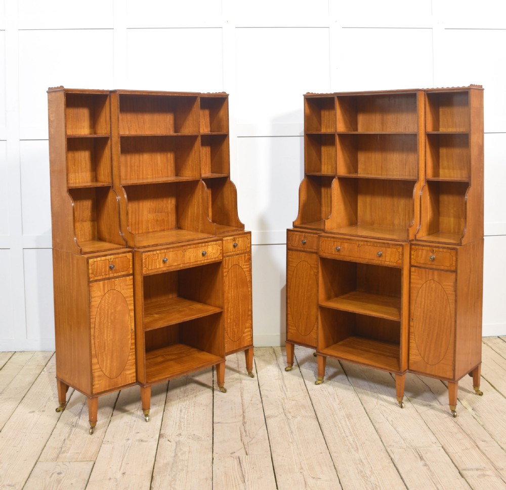 A matching pair of open satinwood breakfront bookcases featuring stepped waterfall shelving, inlaid drawers, and oval panel cupboard doors. View XVIII