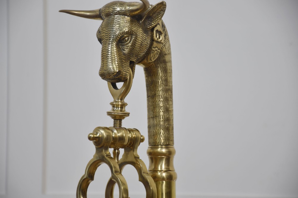 A floor-standing brass balance scale featuring a bull head finial, turned central column, horizontal beam, and two circular brass pans suspended by chains. View IX