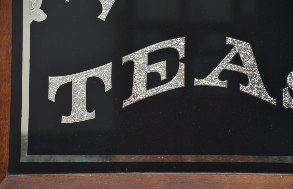 A square Victorian advertising mirror framed in dark wood, featuring silvered arched lettering reading FINE TEAS on a black painted glass ground. View VI