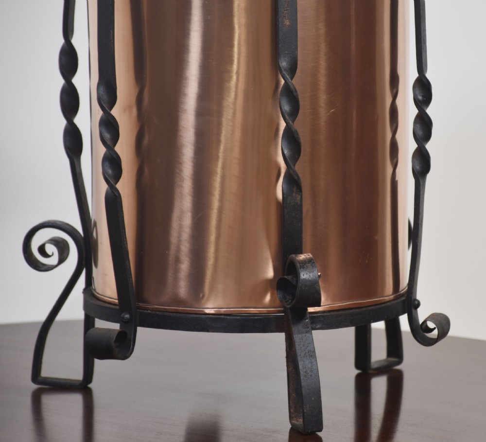 An Arts and Crafts circular copper coal bucket with a fluted lid, supported within a black wrought iron frame with twisted uprights and scroll legs. View IV