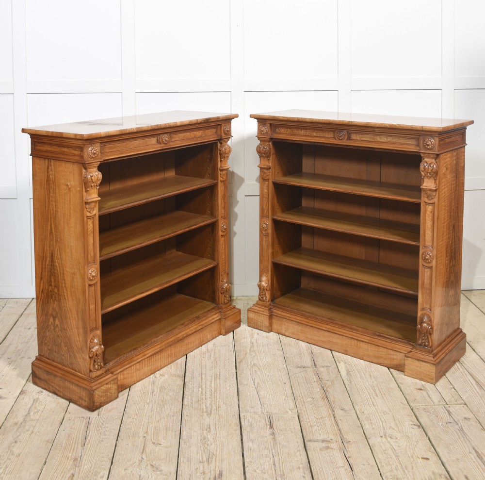A pair of 19th-century walnut open bookcases featuring carved pilasters, rosette details, adjustable shelves, and heavy plinth bases. View VIII