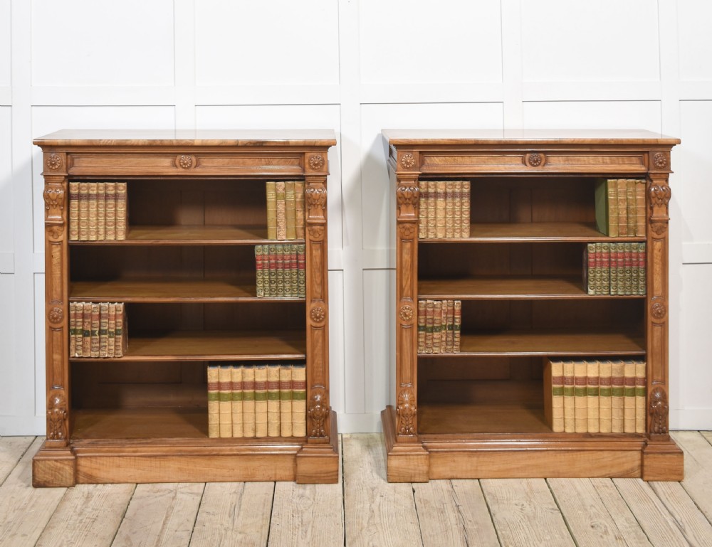 A pair of 19th-century walnut open bookcases featuring carved pilasters, rosette details, adjustable shelves, and heavy plinth bases. View IX