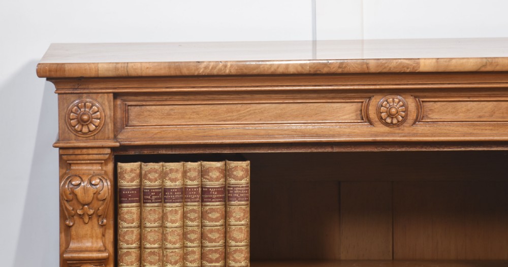A pair of 19th-century walnut open bookcases featuring carved pilasters, rosette details, adjustable shelves, and heavy plinth bases. View XI