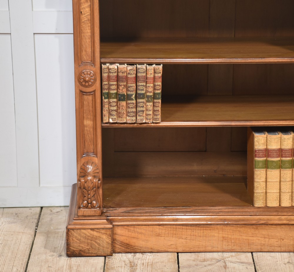 A pair of 19th-century walnut open bookcases featuring carved pilasters, rosette details, adjustable shelves, and heavy plinth bases. View XII