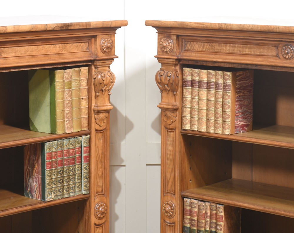 A pair of 19th-century walnut open bookcases featuring carved pilasters, rosette details, adjustable shelves, and heavy plinth bases. View XIV