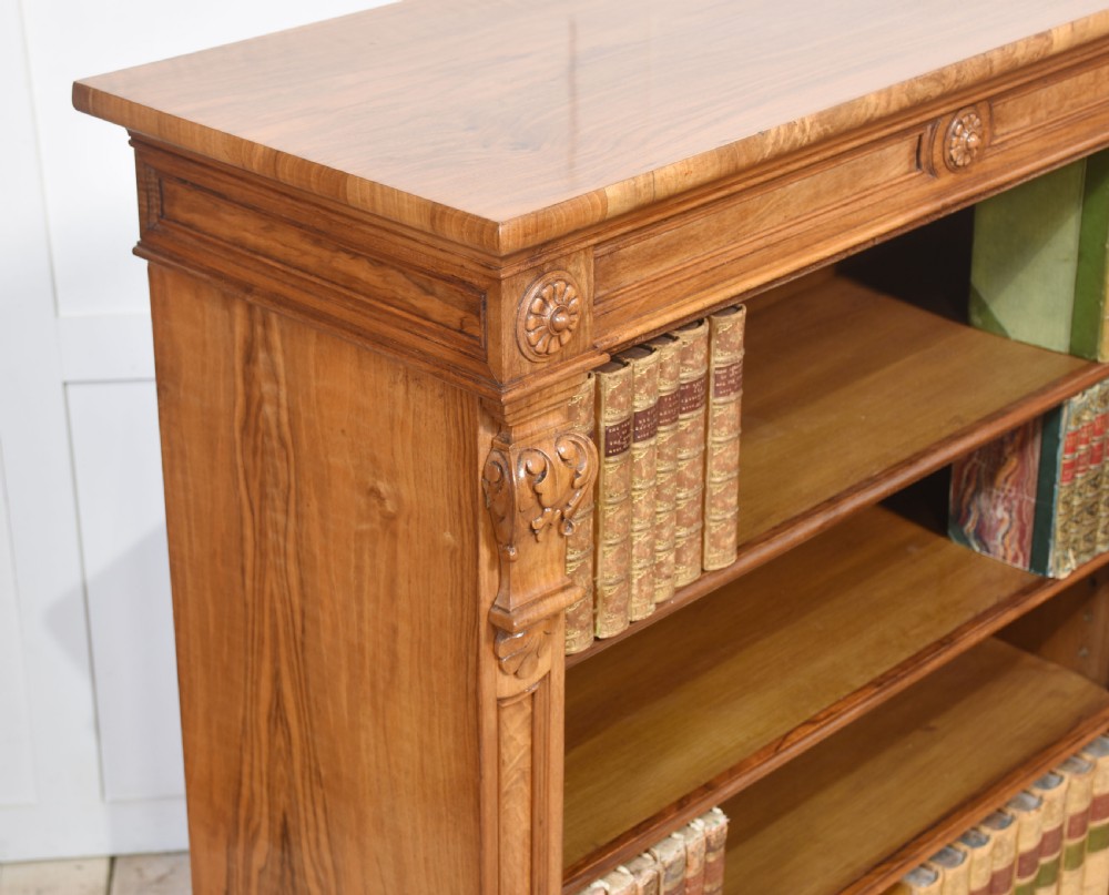 A pair of 19th-century walnut open bookcases featuring carved pilasters, rosette details, adjustable shelves, and heavy plinth bases. View XVI