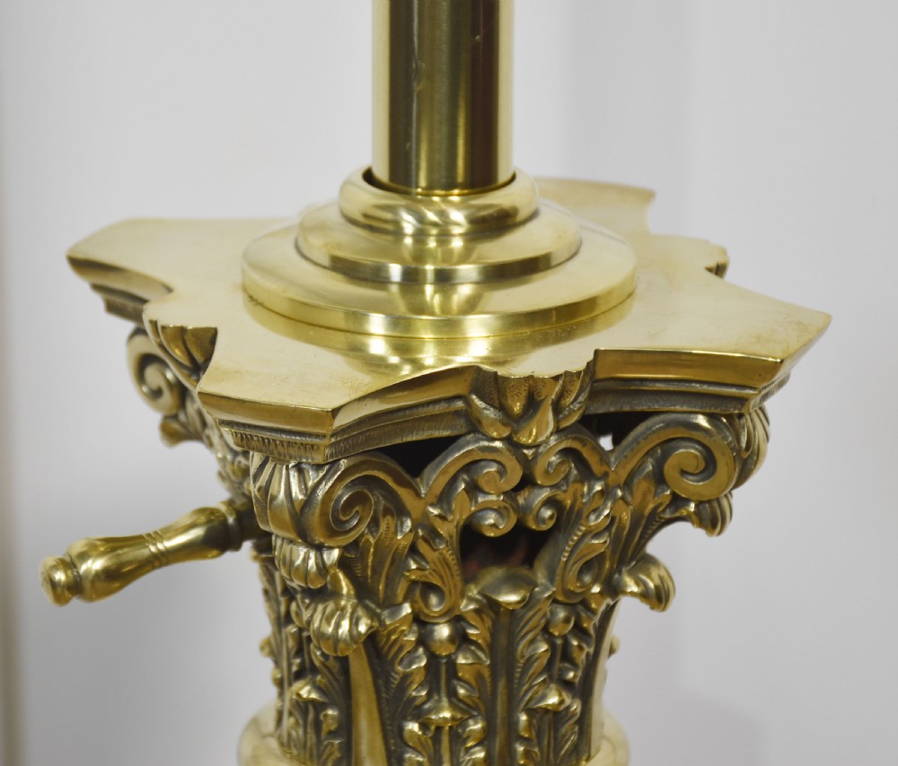 A tall Victorian polished brass standard lamp featuring a fluted column, Corinthian capital, a decorative urn reservoir, and a stepped square base adorned with laurel wreath motifs. View XI