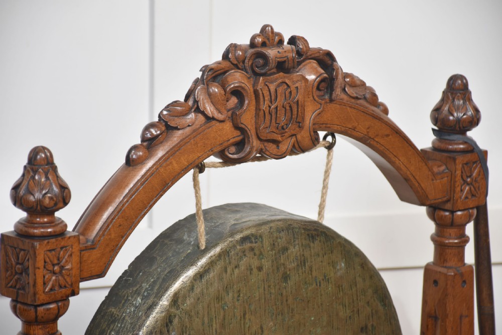 A freestanding carved oak frame featuring turned posts, scroll feet, and a central suspended round brass gong with an attached striker. View III