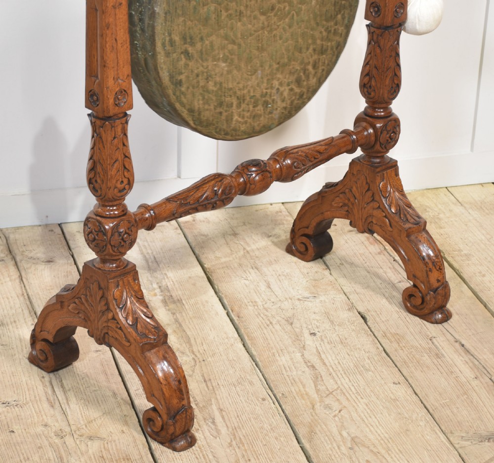 A freestanding carved oak frame featuring turned posts, scroll feet, and a central suspended round brass gong with an attached striker. View IV
