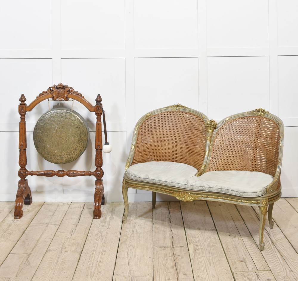 A freestanding carved oak frame featuring turned posts, scroll feet, and a central suspended round brass gong with an attached striker. View IX