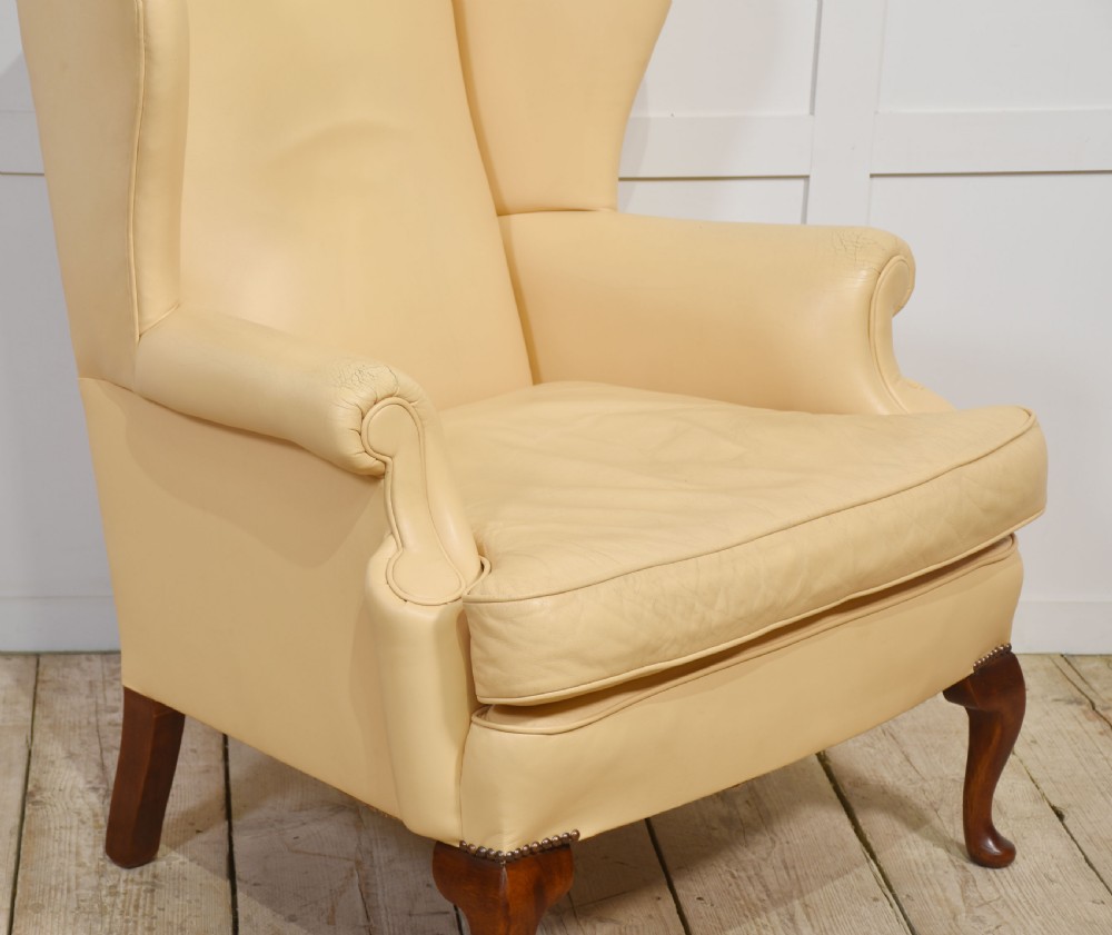 A Georgian style wingback armchair upholstered in cream leather with cabriole front legs. View VII