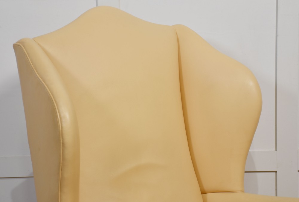 A Georgian style wingback armchair upholstered in cream leather with cabriole front legs. View IX