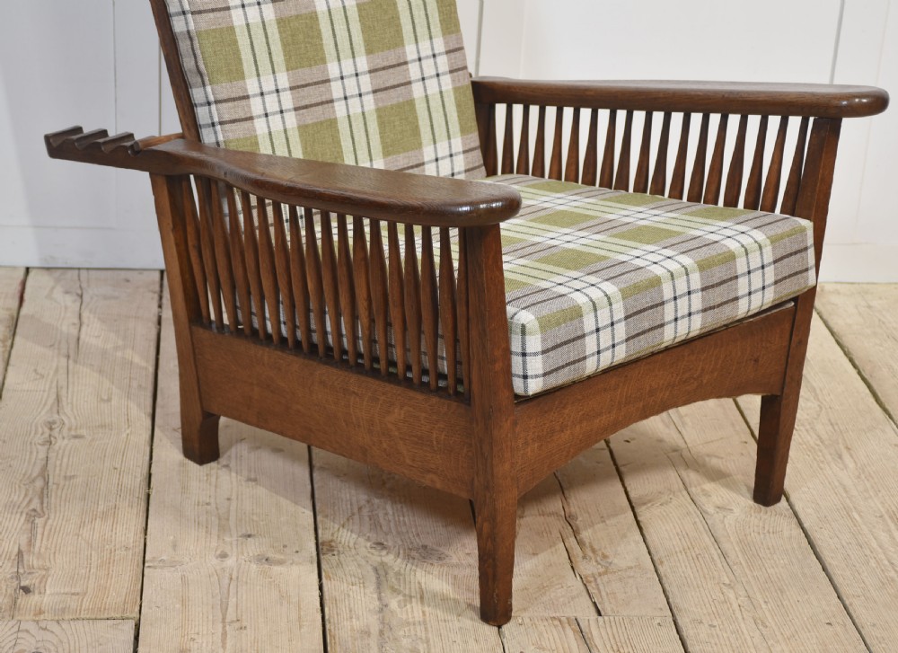 An Arts and Crafts oak reclining armchair featuring vertical side spindles and green tartan plaid fabric cushions. View VII