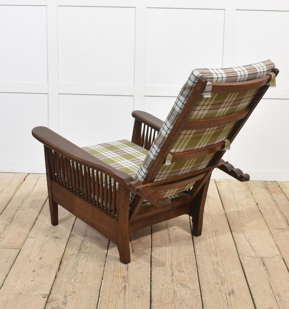 An Arts and Crafts oak reclining armchair featuring vertical side spindles and green tartan plaid fabric cushions. View VIII