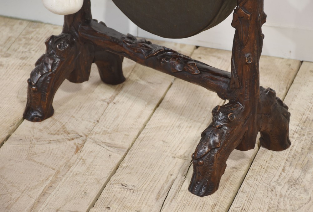 A dark carved oak frame styled with rustic branch motifs holding a central suspended metal circular gong and mallet. View III