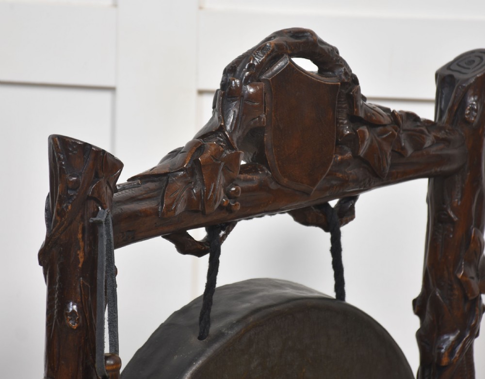 A dark carved oak frame styled with rustic branch motifs holding a central suspended metal circular gong and mallet. View VII