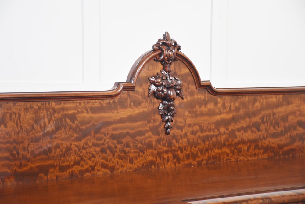 A large Victorian breakfront sideboard crafted from figured mahogany featuring four panelled doors, carved scroll brackets, and an arched cresting rail with carved floral motifs. View II