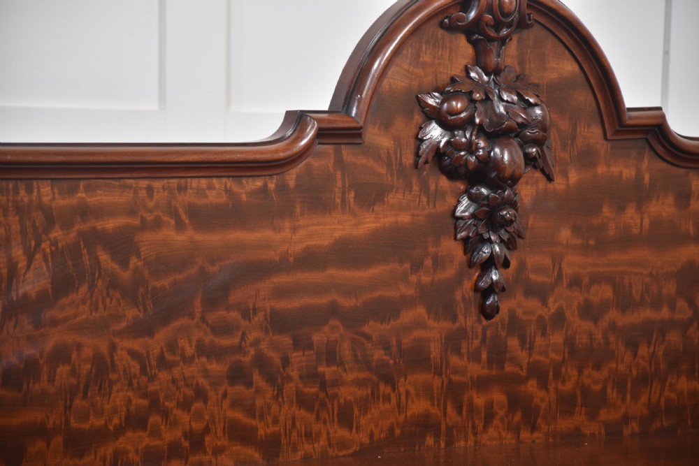 A large Victorian breakfront sideboard crafted from figured mahogany featuring four panelled doors, carved scroll brackets, and an arched cresting rail with carved floral motifs. View V